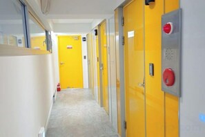 A hallway with yellow doors, a fire alarm, and a fire extinguisher. - Look Home Guesthouse in Myeong-dong (Seoul)