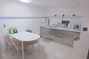 A modern kitchen with a white table, chairs, and a microwave. - Look Home Guesthouse in Myeong-dong (Seoul)