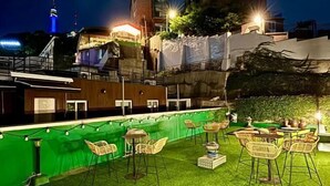 An outdoor bar area with green artificial grass, wicker chairs, and tables. - Look Home Guesthouse in Myeong-dong (Seoul)
