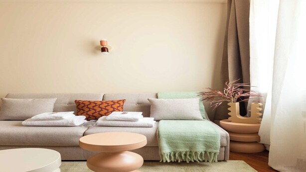 A modern living room with a sofa, a round table, and a decorative vase.