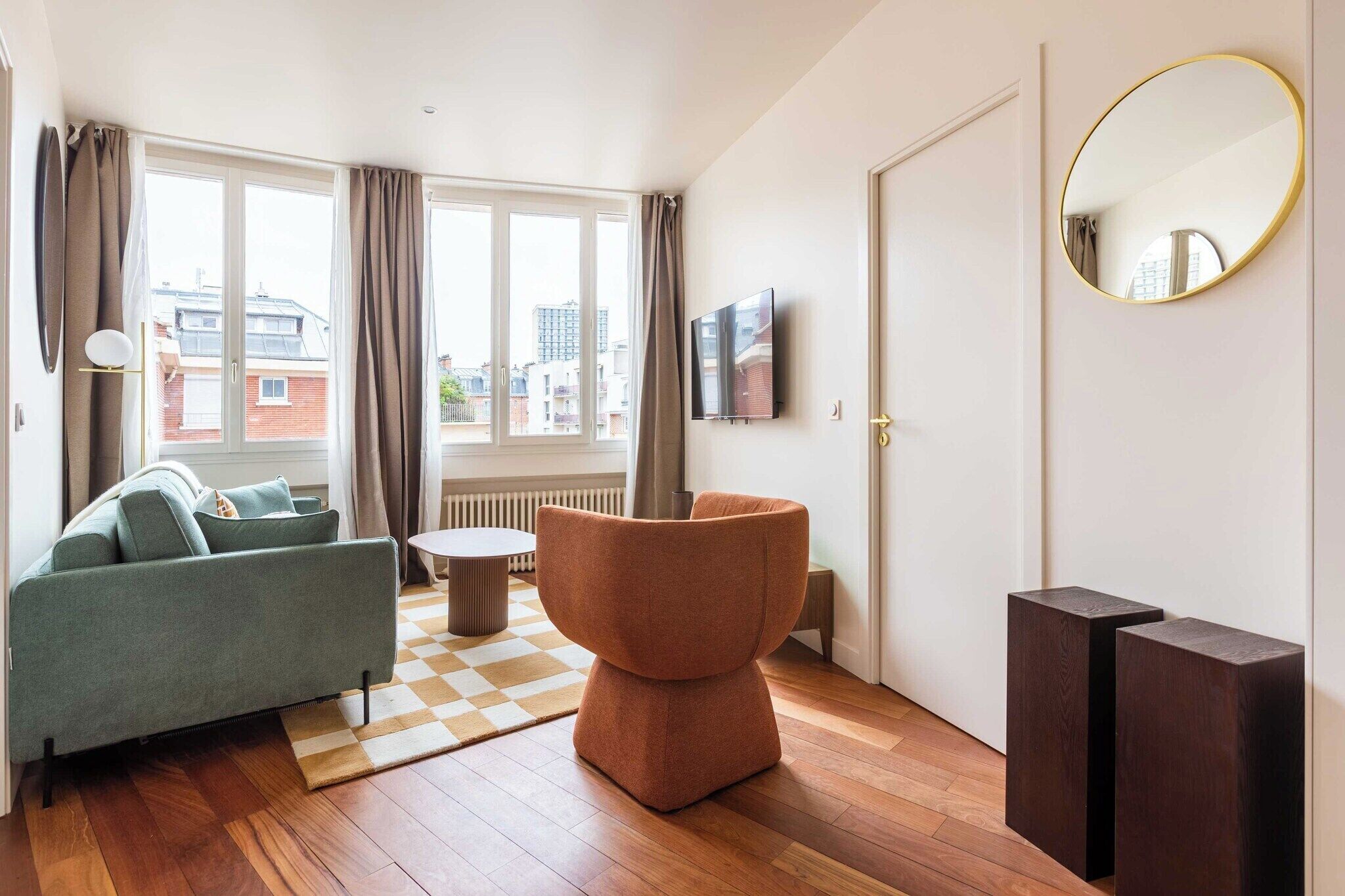 Ein modernes Wohnzimmer mit einer Couch, einem runden Hocker und einem Flachbildfernseher.
