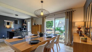 A modern kitchen with a dining area, large windows, and a view of the garden. - Maison Er Menhir by Interhome (Plouhinec Morbihan)