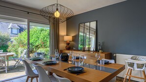 A modern dining area with a wooden table, white chairs, and a pendant light. - Maison Er Menhir by Interhome (Plouhinec Morbihan)