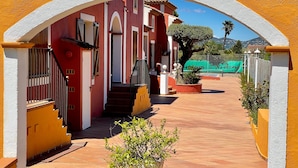 A red building with a white archway, a staircase, and a potted plant in the foreground. - Villa '23 Maria Callas' with Private Terrace, Wi-Fi and Air Conditioning (Ramatuelle)