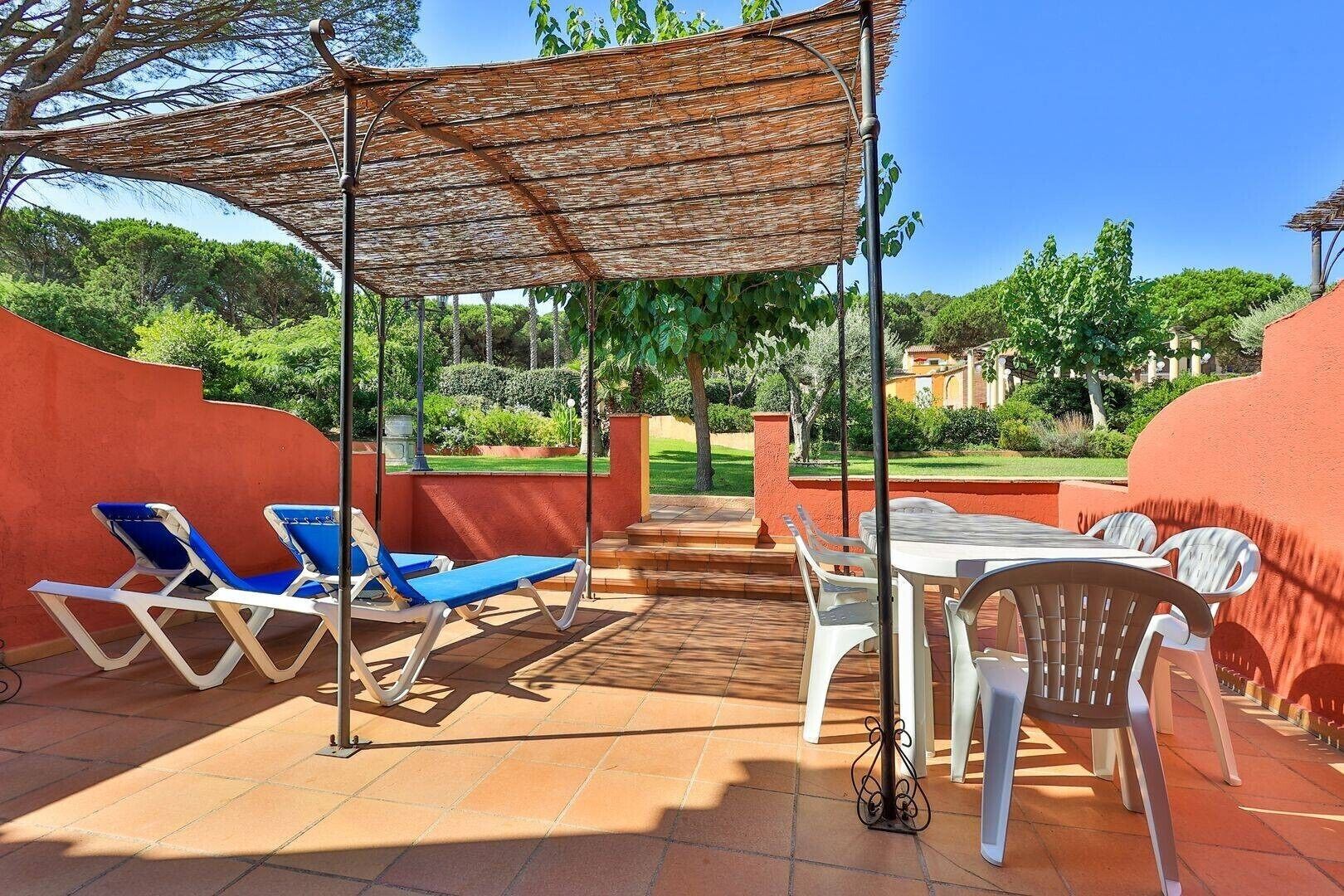 Une terrasse extérieure avec des chaises longues, une table et une pergola.