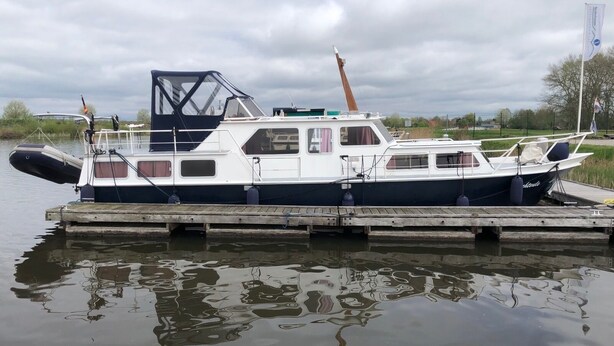 Un bateau noir et blanc était amarré à un quai en bois, avec un ciel nuageux en arrière-plan.