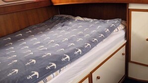 Une petite cabine comprenant un lit, une fenêtre et un petit placard.