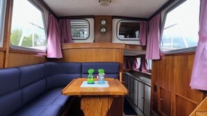 Un intérieur de camping-car compact avec un canapé bleu, une table en bois et un coin cuisine.
