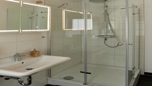 A modern bathroom with a glass-enclosed shower, a white sink, and a mirror with integrated lighting. - Haus Freigeist - zum Gartenblick (Thale)