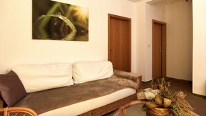 A cozy room with a white sofa, a wooden door, and a wall-mounted painting. - Haus Freigeist - zum Gartenblick (Thale)