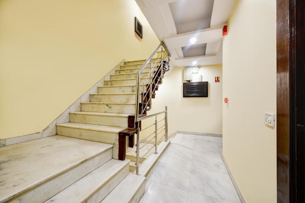 A staircase with marble steps and metal railings leading to a landing with a ceiling light fixture.