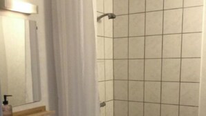 A bathroom with a sink, mirror, and shower area. - Marsktures motel (Højer)