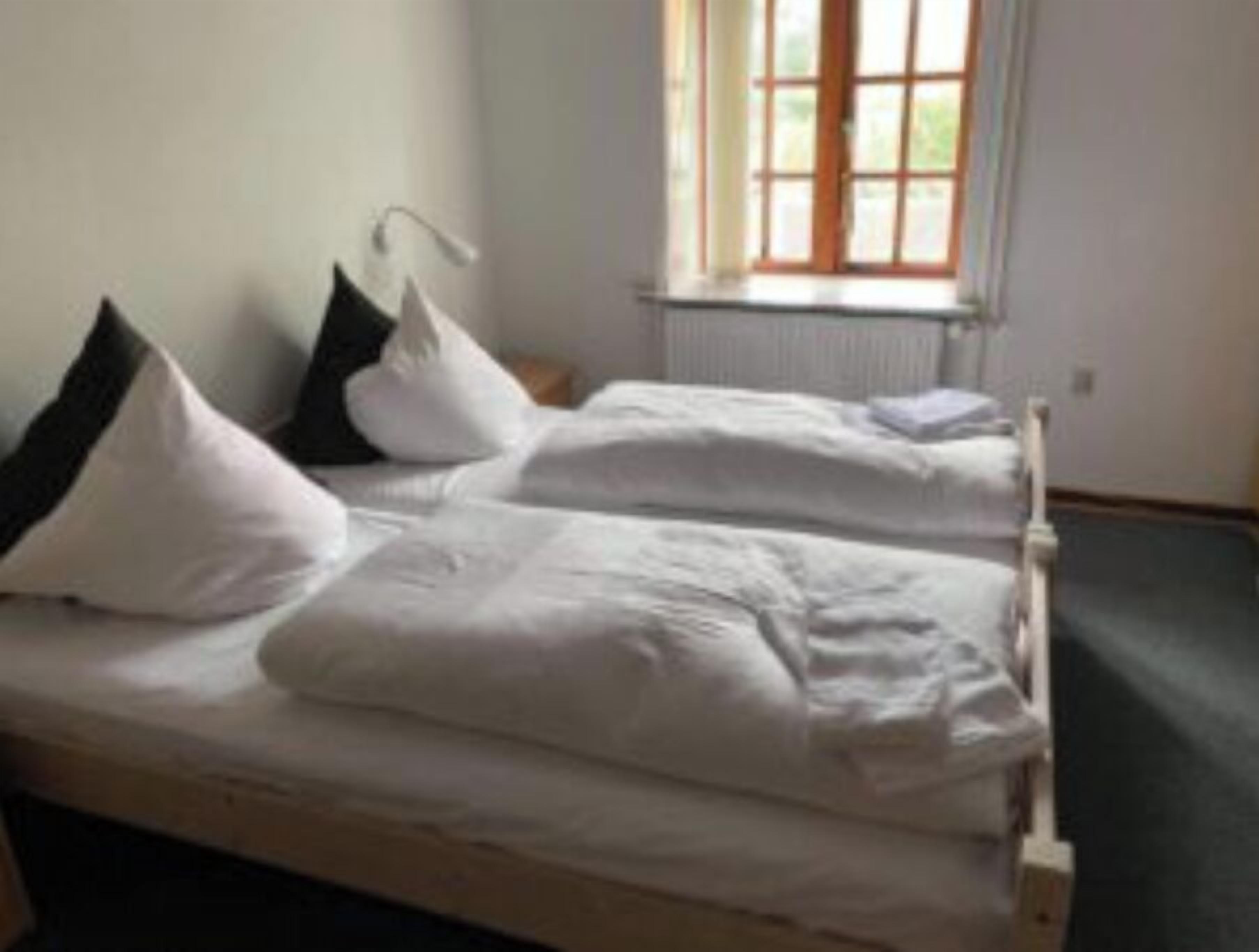 Ein Zimmer mit zwei Einzelbetten, weißer Bettwäsche, einem Fenster mit Blick und einer Heizung.