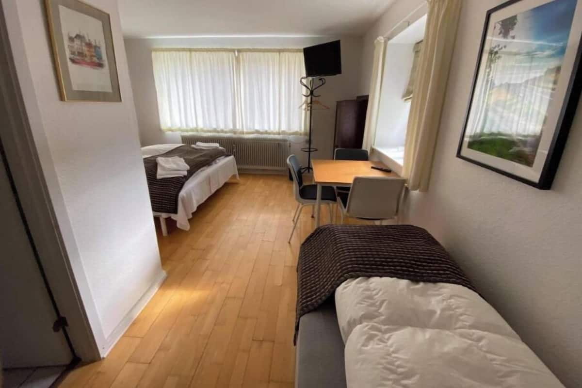 A hotel room with a bed, a desk, a chair, a television, and a window with curtains.