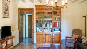 Ein Wohnzimmer mit Bücherregal, Fernseher, Sessel und Tisch.
