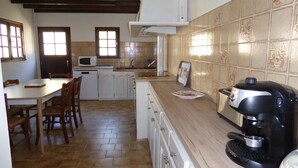 Eine Küche mit Esstisch, Stühlen, einer Mikrowelle, einem Toaster und einer Kaffeemaschine.