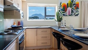 A kitchen with a stove, oven, and cabinets. There is a window with a view of mountains.