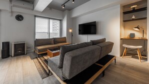 A modern living room with a sofa, a flat-screen TV, a fireplace, and a wooden floor. - LUXIA 601 (Sapporo)