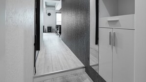 A modern hallway with a wooden floor, a dark textured wall, and a white cabinet with a shelf. - LUXIA 601 (Sapporo)