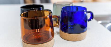 Three glass mugs with cork bases on a white countertop.