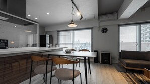 A modern kitchen with a central island, dining chairs, a sofa, and large windows with a city view. - LUXIA 601 (Sapporo)