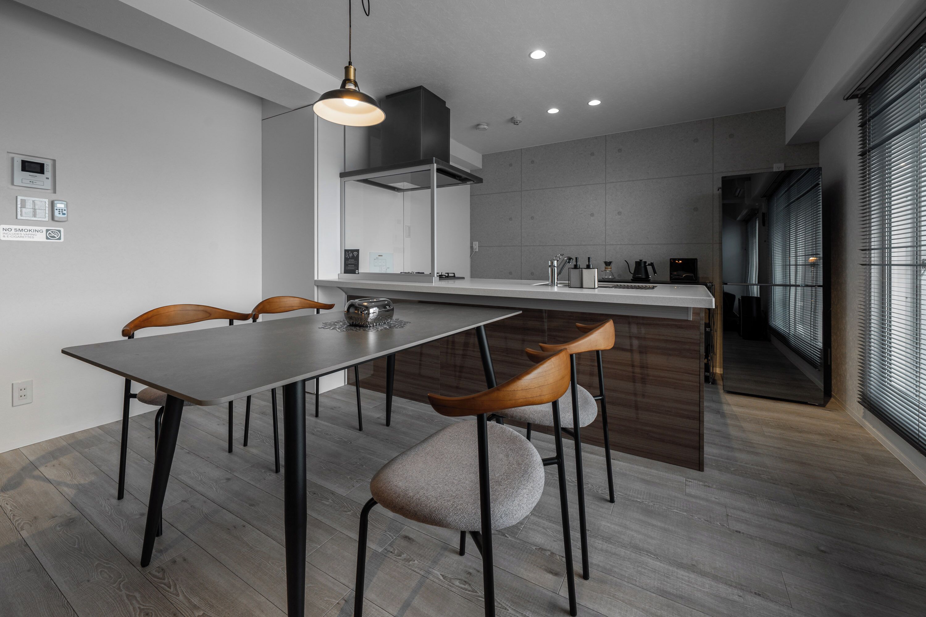 Cocina moderna con una isla central, sillas de madera y una lámpara colgante.