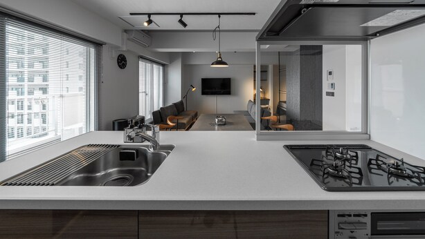A modern kitchen with a large island, stainless steel appliances, and a dining area with a sofa and table. - LUXIA 601 (Sapporo)