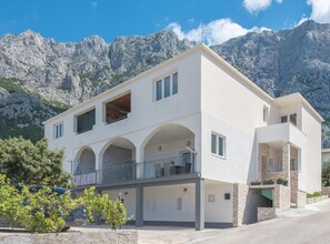 A modern two-story building with a balcony, set against a mountainous backdrop. - Sea View Top Hill (Makarska)
