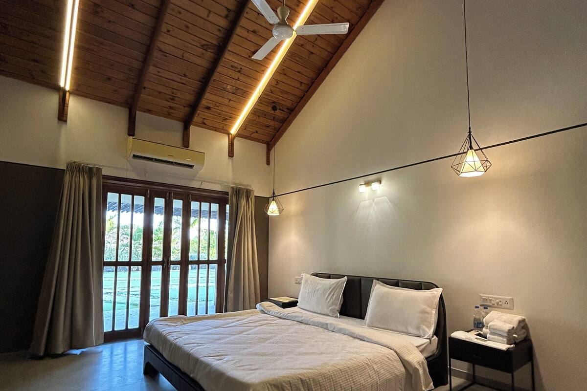 A bedroom with a large bed, a ceiling fan, and a nightstand with a lamp.