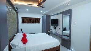 Una habitación de hotel con una cama, un ventilador de techo, un televisor montado en la pared y un espejo sobre la cama.