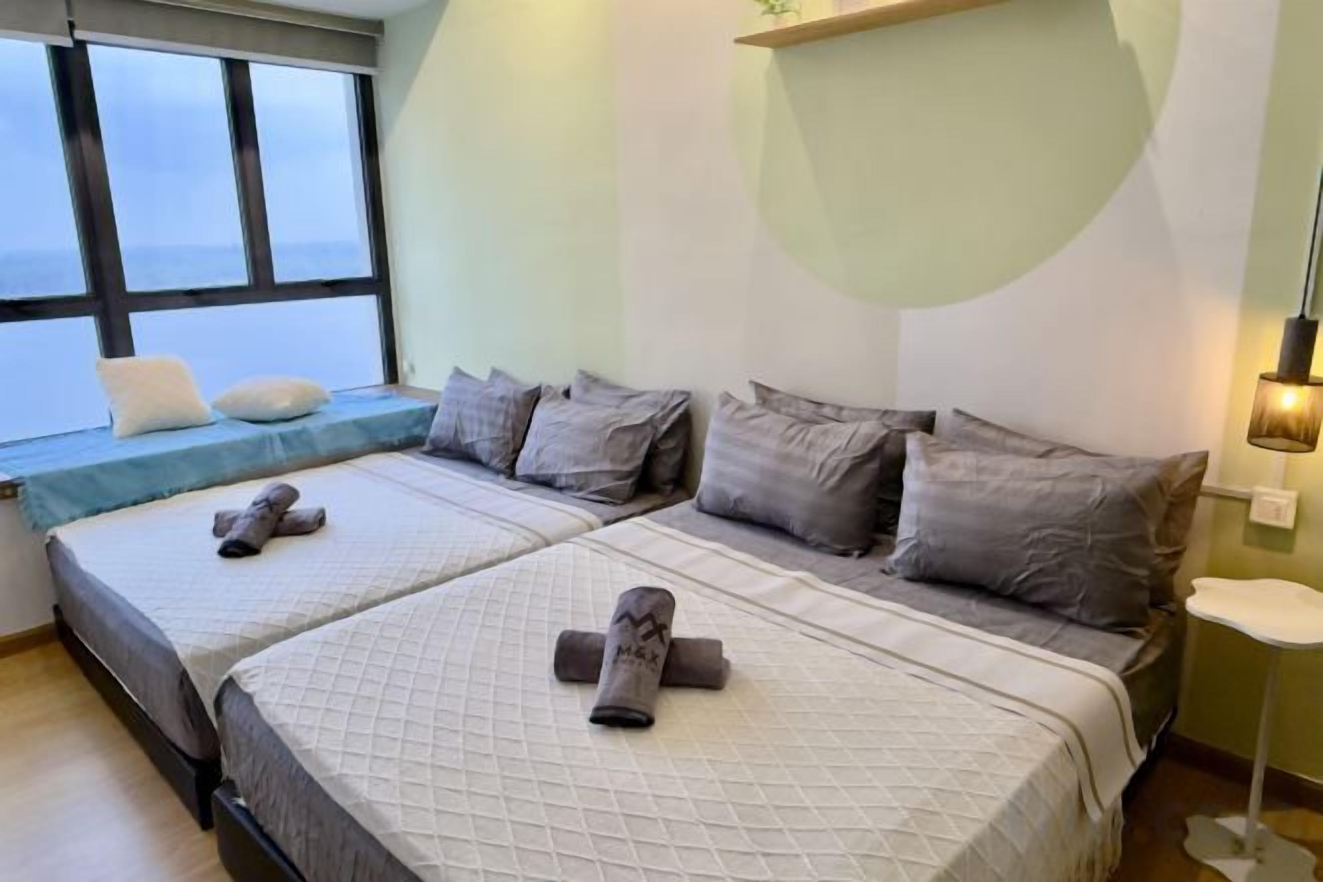 A hotel room with two beds, a window with a view, and a bedside table with a lamp.