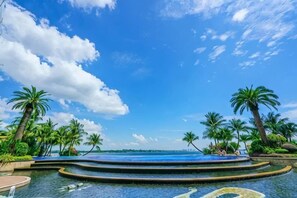 A pool with a view of the ocean, surrounded by palm trees. - Full Sea View Country Garden Danga Bay 11-13pax (Johor Bahru)