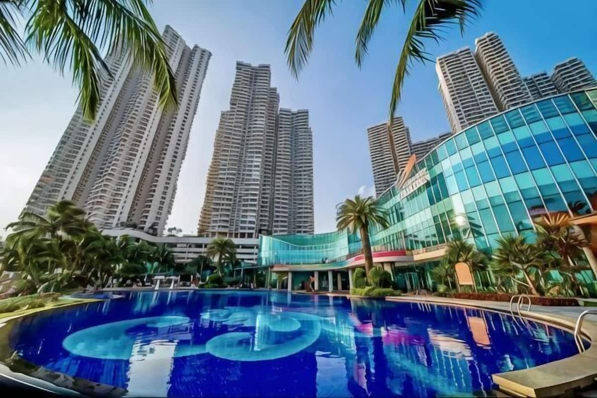 Ein Pool mit kreisförmigem Design, umgeben von hohen Wohnhäusern und Palmen.