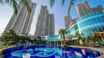 A swimming pool with a circular design, surrounded by tall residential buildings and palm trees.