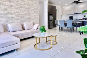 A modern living room with a sofa, a coffee table, and a dining area with chairs and a table. - Full Sea View Country Garden Danga Bay 11-13pax (Johor Bahru)