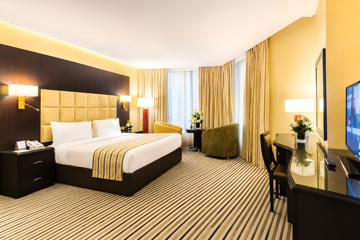 Una habitación de hotel con una cama grande, un escritorio, una silla y un televisor.