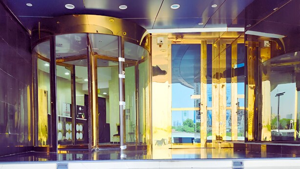 A modern building entrance with glass doors and a staircase leading up. - Bloom Hotel (Kuwait City)