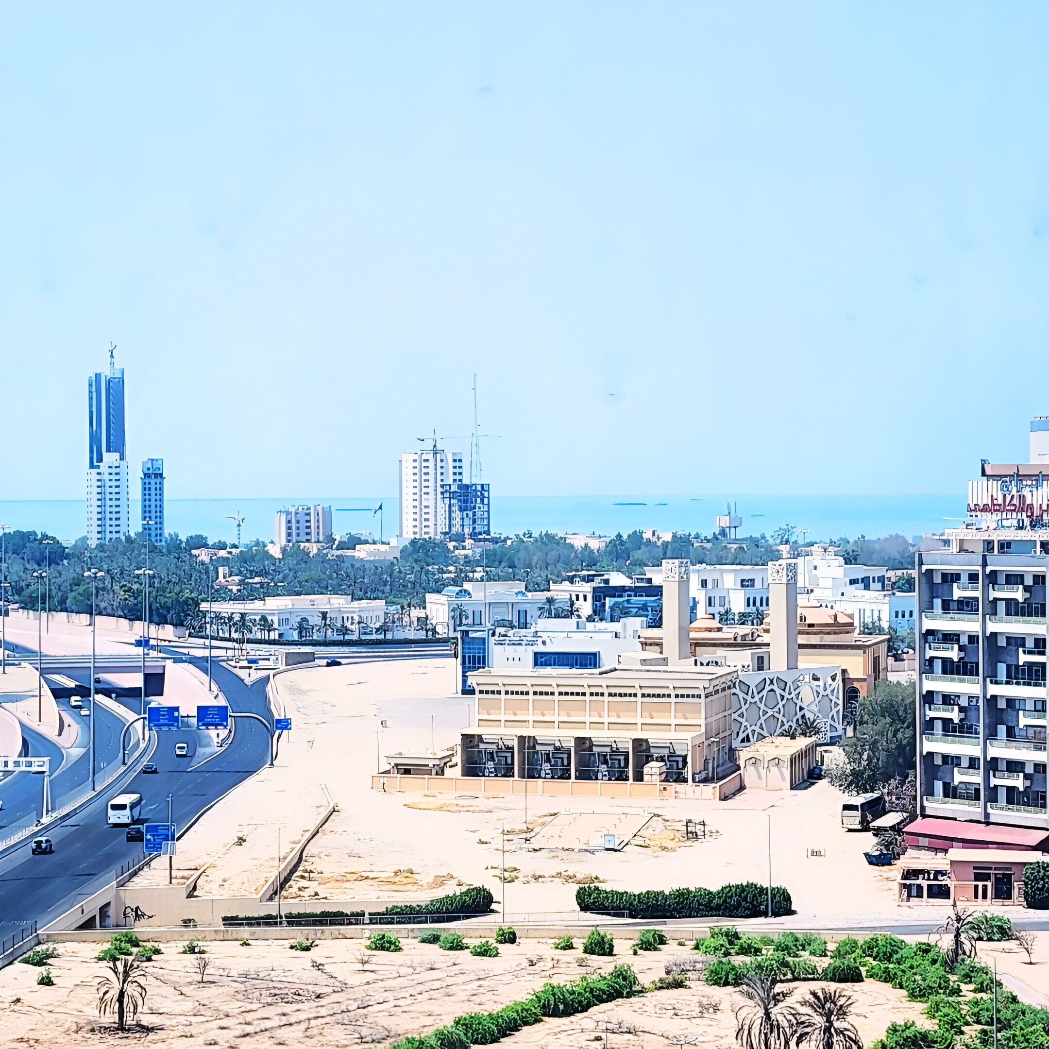 Un paisaje urbano con edificios modernos, una autopista y una playa al fondo.