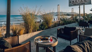 A beachside restaurant with outdoor seating, a view of the ocean, and a sign for 'Horizon Restaurant & Beach Bar'.