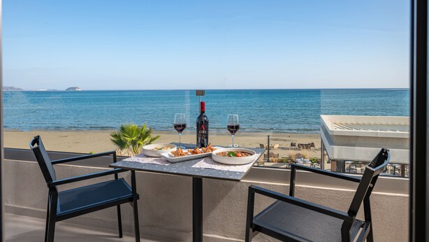 A table with food and drinks on a balcony overlooking the sea.