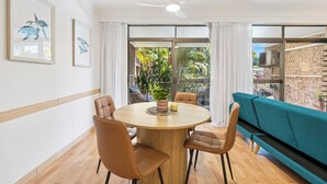A dining area with a round table, four chairs, and a ceiling fan.