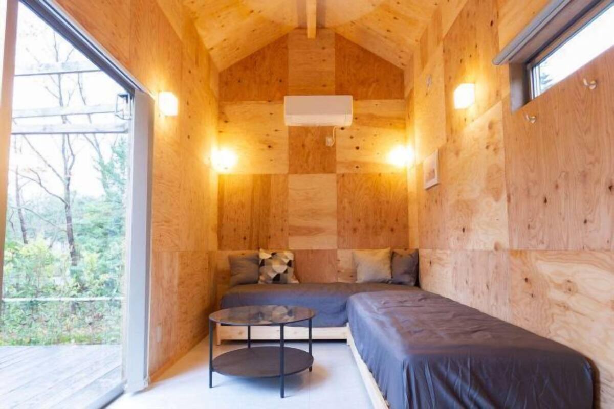 Une cabane en bois accueillante, avec un lit, une petite table et une fenêtre.