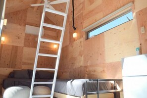 Quarto compacto de madeira com beliches, escada, janela e ventilador de teto.