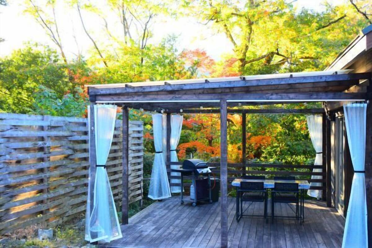 Une terrasse en bois dotée d’une pergola, d’un barbecue extérieur et d’un espace salon.