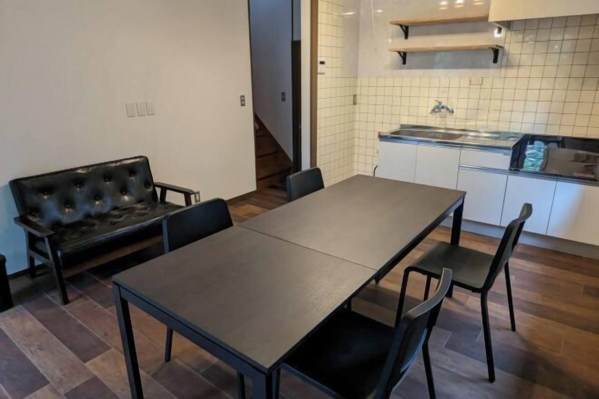 Un coin repas avec une table et des chaises, un canapé, une cuisine avec un évier et un escalier.