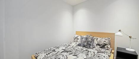 A neatly made bed with a patterned bedspread, a bedside lamp, and a nightstand.