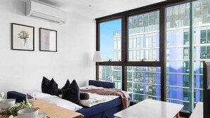 Una habitación de hotel moderna con un ventanal grande, una cama, una mesa de comedor y una pequeña mesa.