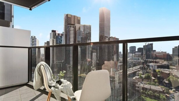 A balcony with a city view, a white chair, and a table with a plant and a towel.