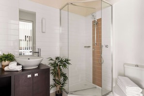 A modern bathroom with a glass-enclosed shower, a large sink, and a dark wooden vanity.