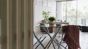 Et moderne spiseområde med et glasbord, metalstole og en potteplante.